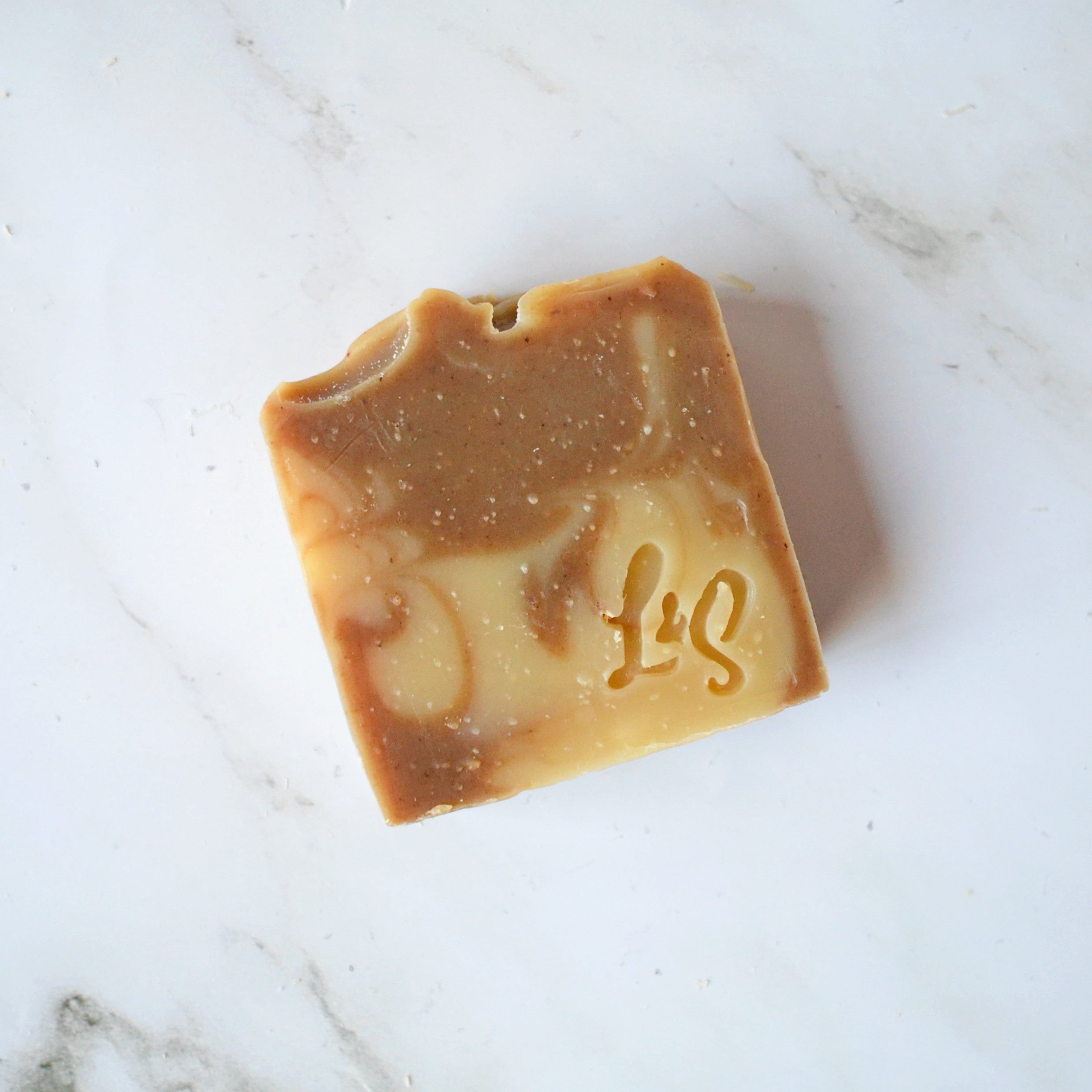 a bar of handmade matcha green tea soap on a white marble background