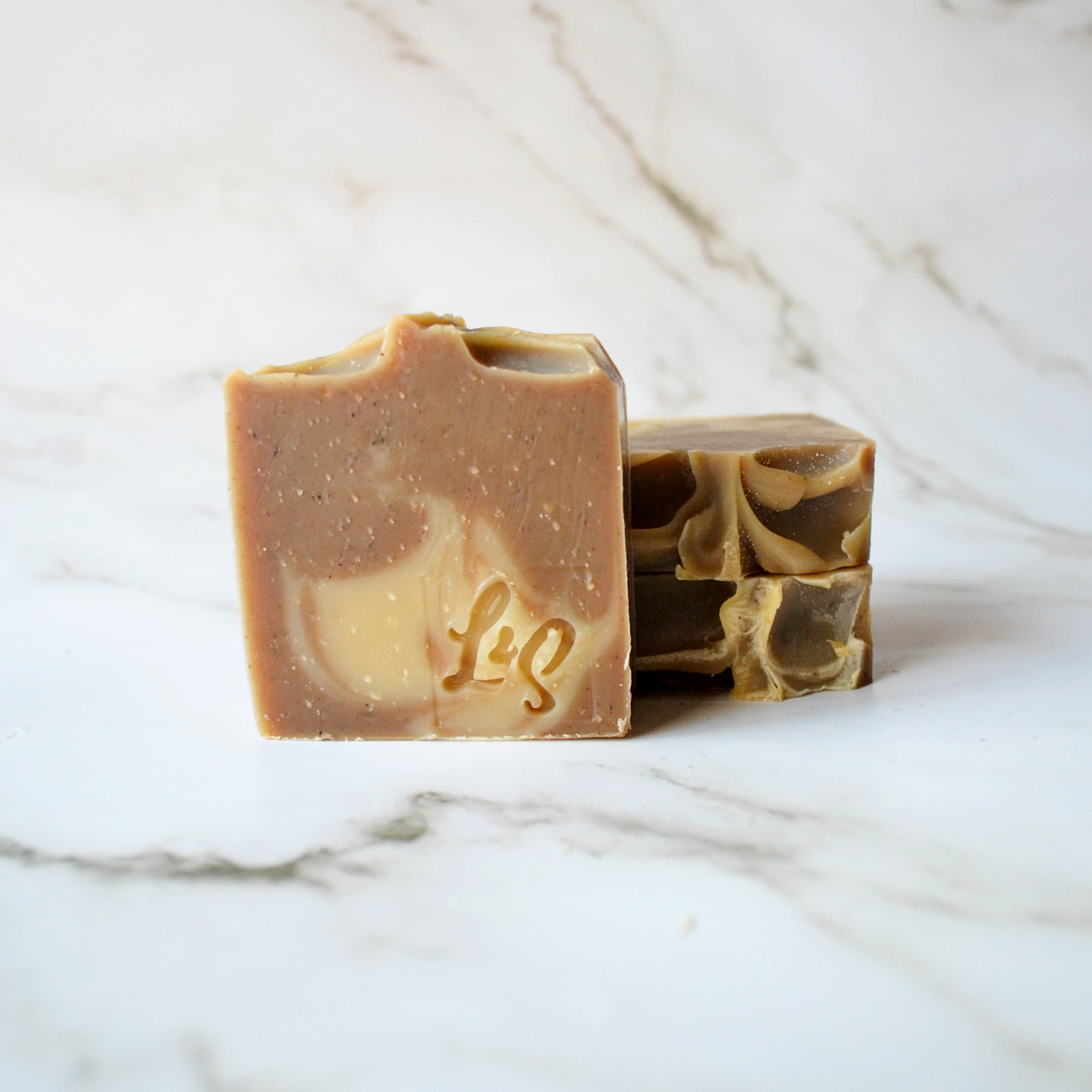 three bars of handmade matcha green tea soap on a white marble background